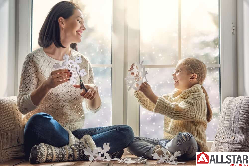 Mother and daughter making snowflakes near energy efficient windows