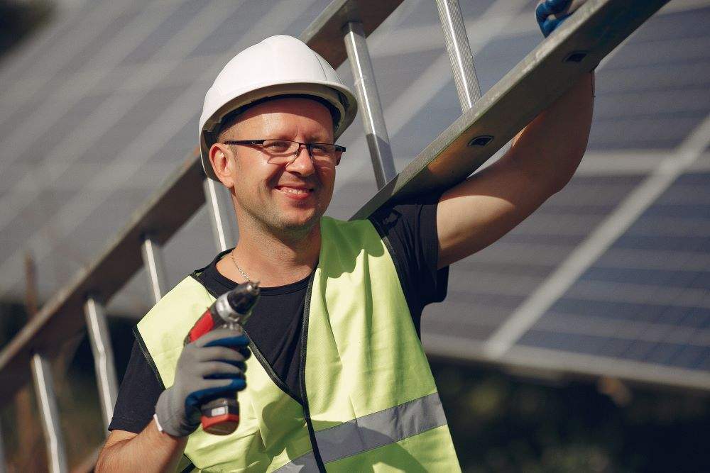 man with white helmet near solar panel