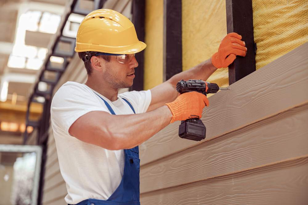 male builder using power drill at construction site