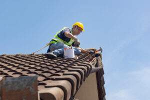 worker man repairing eaves and tile of the old roof